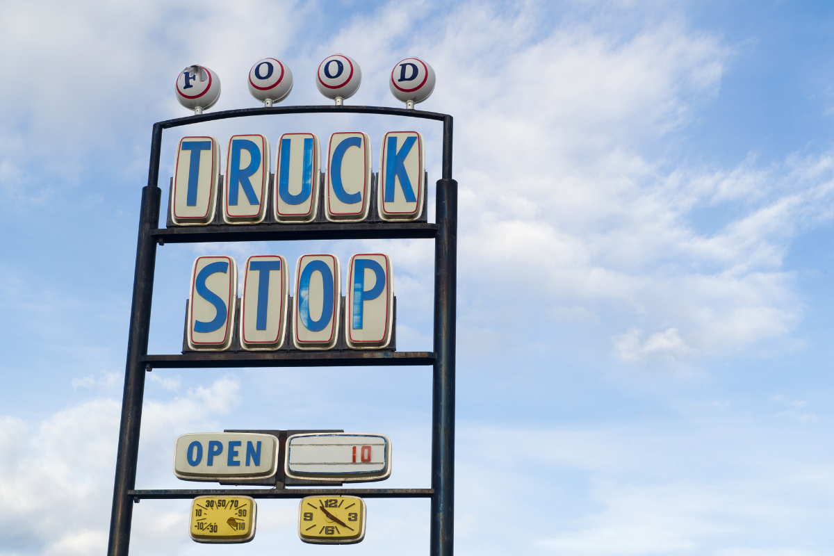 Truck stop sign welcomes visitors on a sunny day.