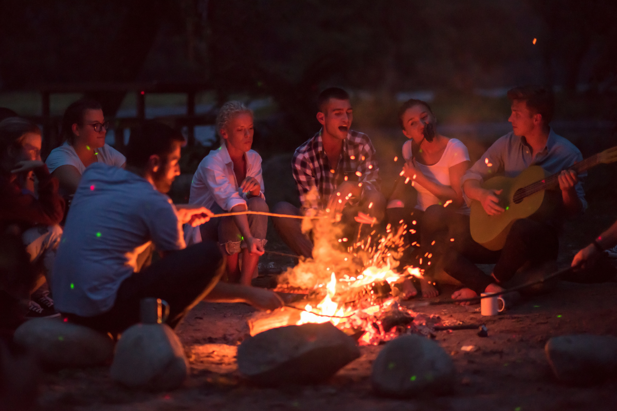 Adults sitting around a campfire.
