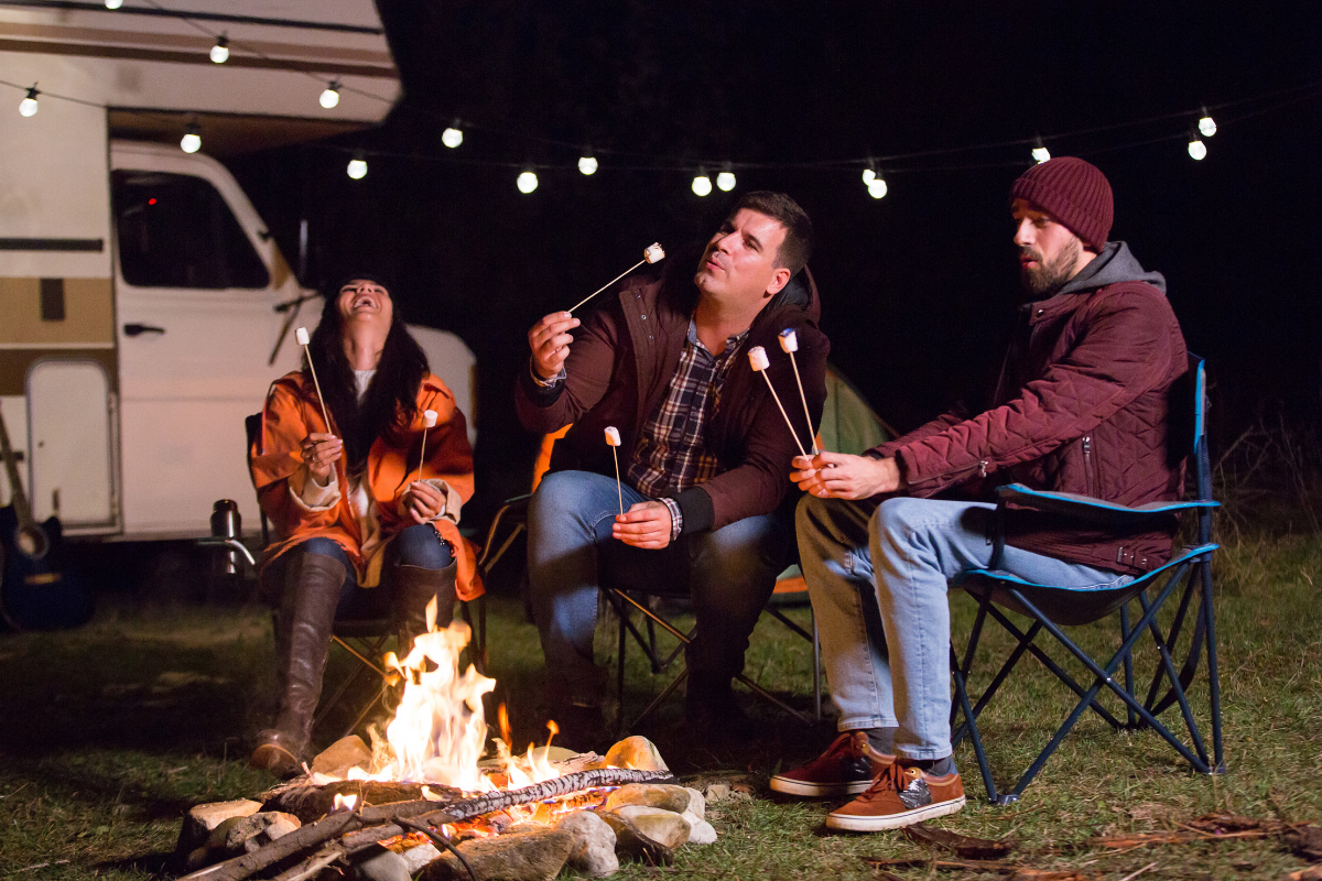 Group of friends laugh at campfire jokes.
