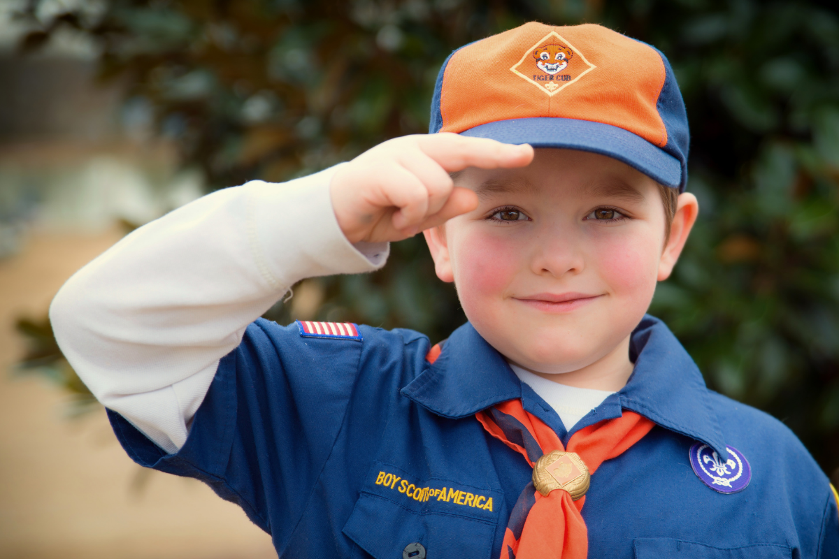 Boy scout in uniform salutes.