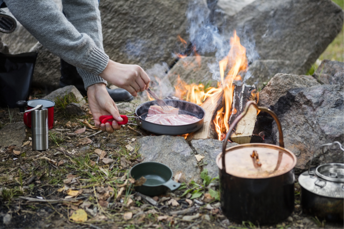 Camper cooks a meal over the fire.
