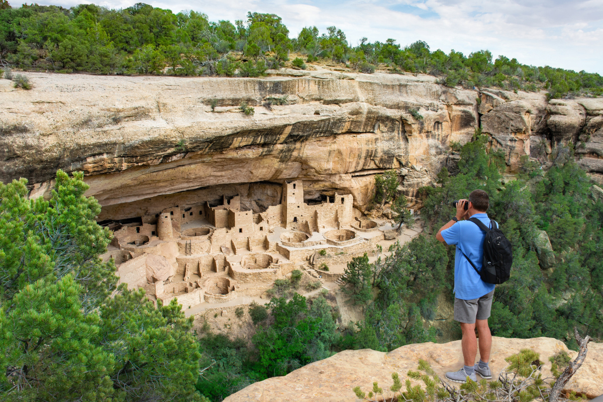 Man on vacation using his camera. videotaping historical cliff dwellings. Ancestral. Puebloan archaeological sites. Cliff Palace ruins at Mesa Verde National Park, Colorado, USA.