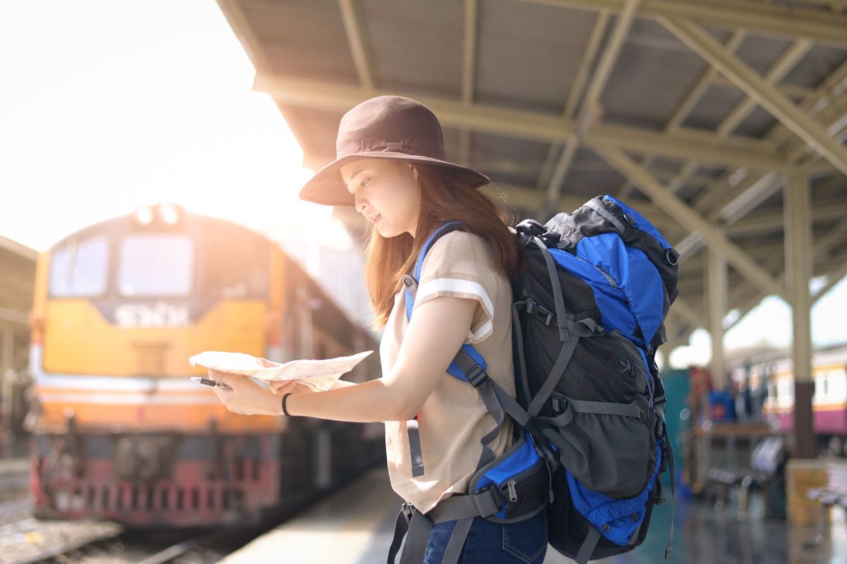 young woman is planning to travel by train while standing at station