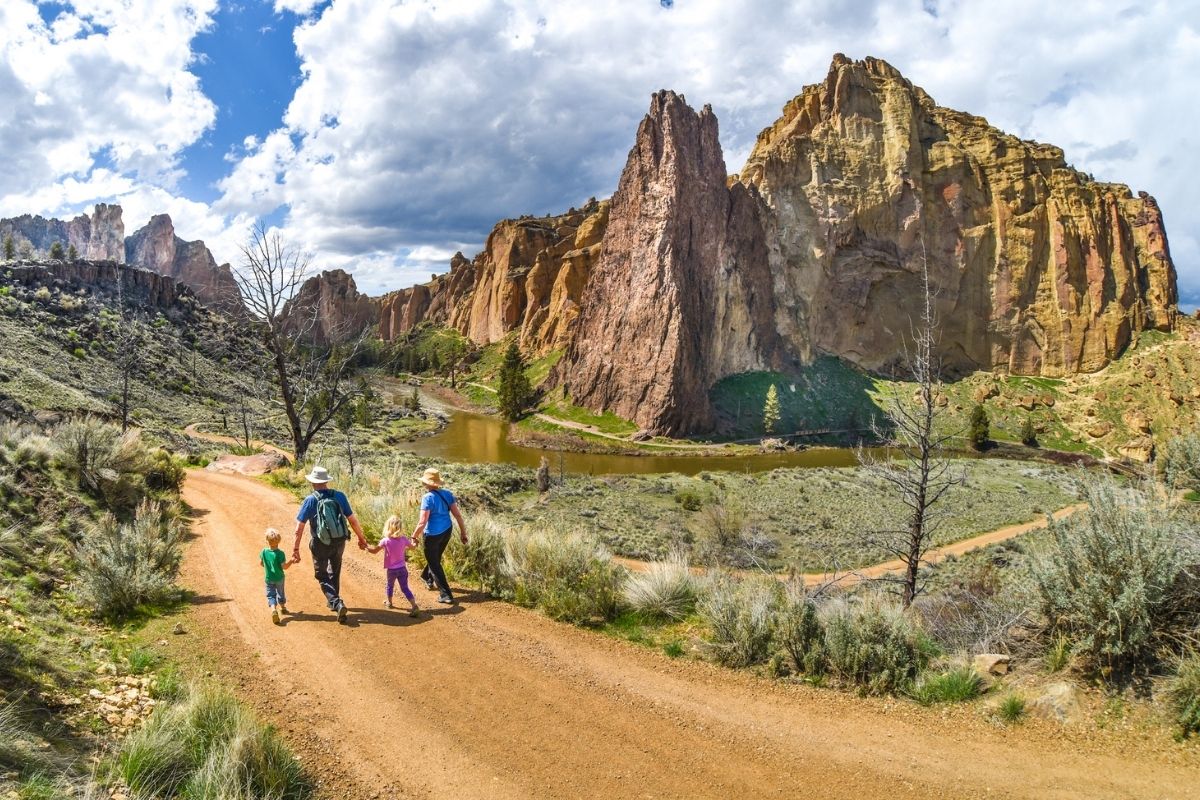 Two children hold hands with their grandparents while hiking at Smith Rock State Park, Oregon.