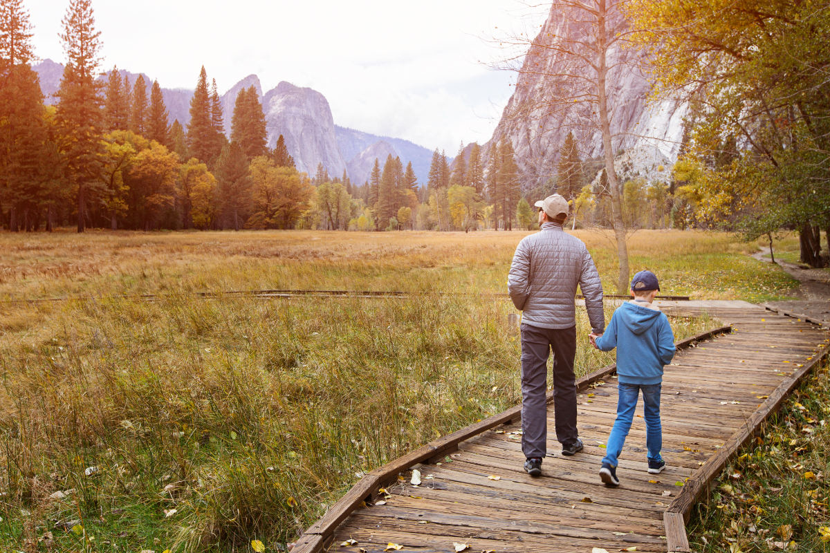 active family of two, father and son, enjoying walking in yosemite national park, california, at autumn