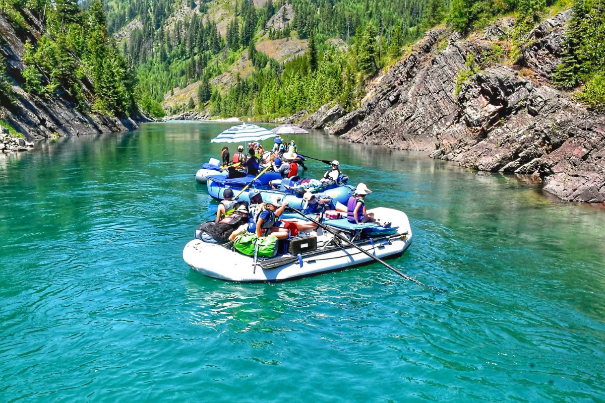 two rafting boats full of people float down blue water
