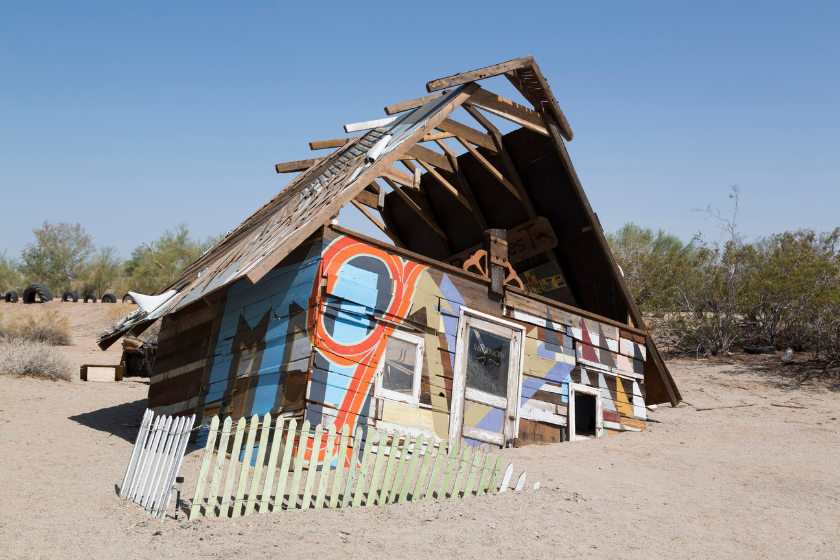 a colorful house sunk in sand in slab city
